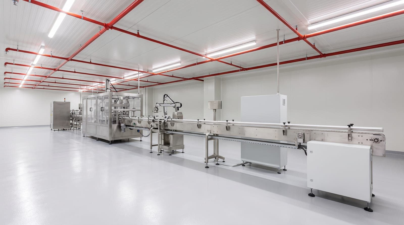 Usine agroalimentaire moderne, ligne de conditionnement inox, réseau sprinkler rouge sous un plafond blanc hygiénique, sol résine clair
